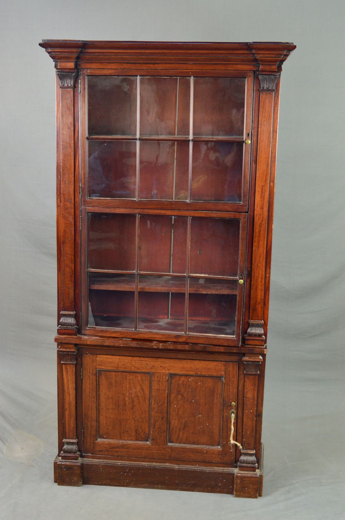 AN EARLY 19TH CENTURY MAHOGANY BOOKCASE, the moulded cornice above two glazed doors each with six