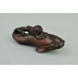A MEIJI PERIOD CARVED WOODEN NETSUKE, in the form of a fish surmounted by a monkey, both with