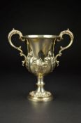 A VICTORIAN SILVER TWIN HANDLED TROPHY CUP, of lobed baluster form, gilt interior, repousse