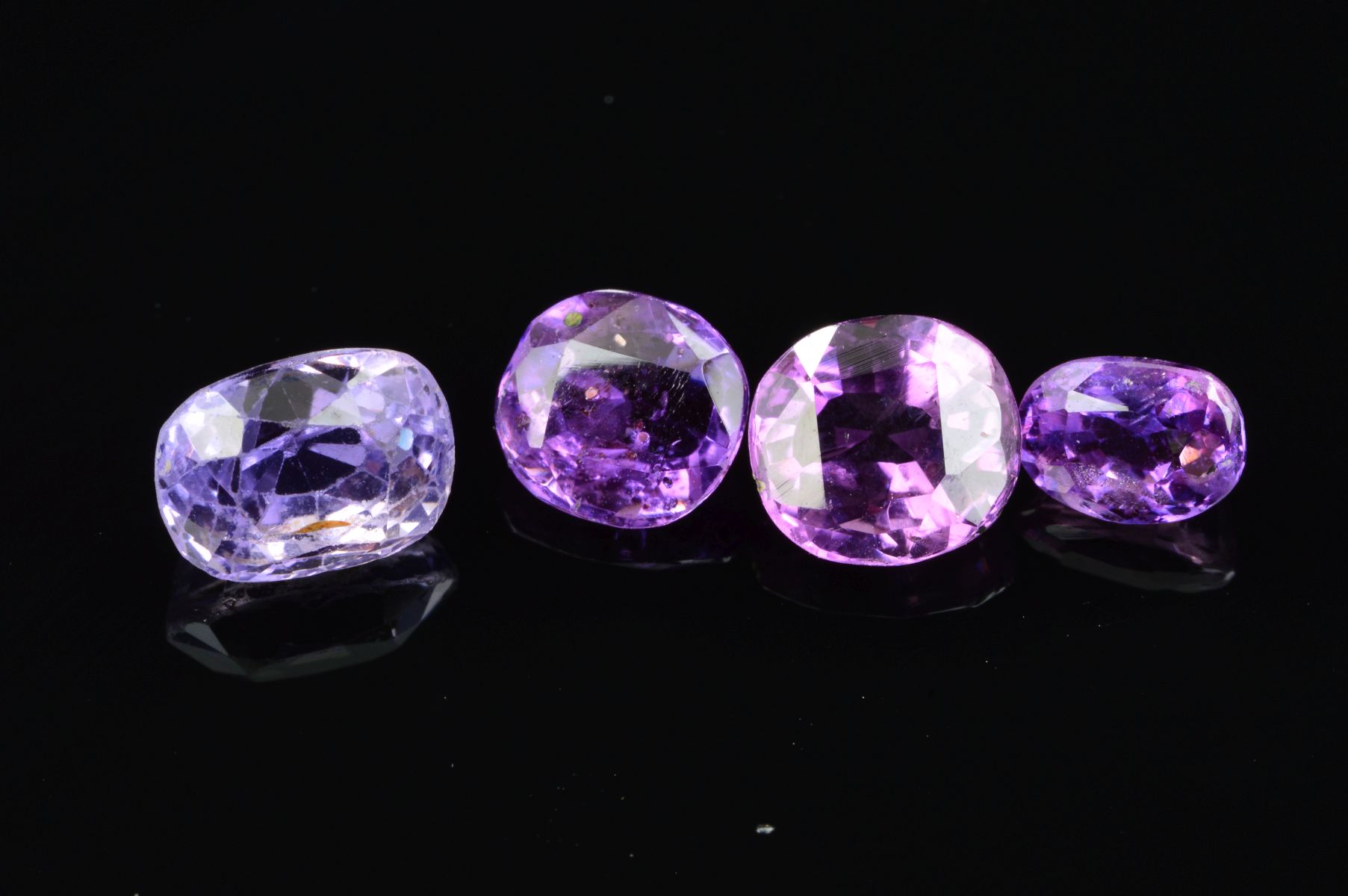 FOUR MAUVE/PURPLE VARI-CUT SAPPHIRES, one old cushion cut 7.8mm x 5.8mm, weighing 2.33ct, please