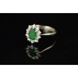 A LATE 20TH CENTURY 18CT WHITE GOLD EMERALD AND DIAMOND OVAL CLUSTER RING, oval mixed cut emerald