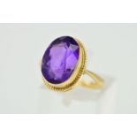 A 9CT GOLD AMETHYST RING, the oval amethyst within a collet setting to the rope twist surround