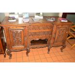 AN EARLY 20TH CENTURY HEAVILY CARVED OAK SIDEBOARD, with two foliate decorated panelled doors