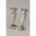 A PAIR OF GEORGE V SILVER CANDLESTICKS, circular sconces, on shaped square tapering stems to