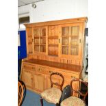 A LARGE EARLY 20TH CENTURY PITCH PINE KITCHEN DRESSER, the top section with triple glazed sliding