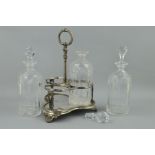 A SILVER PLATED TANTALUS, of trefoil form, with loop handle containing three cut glass decanters and