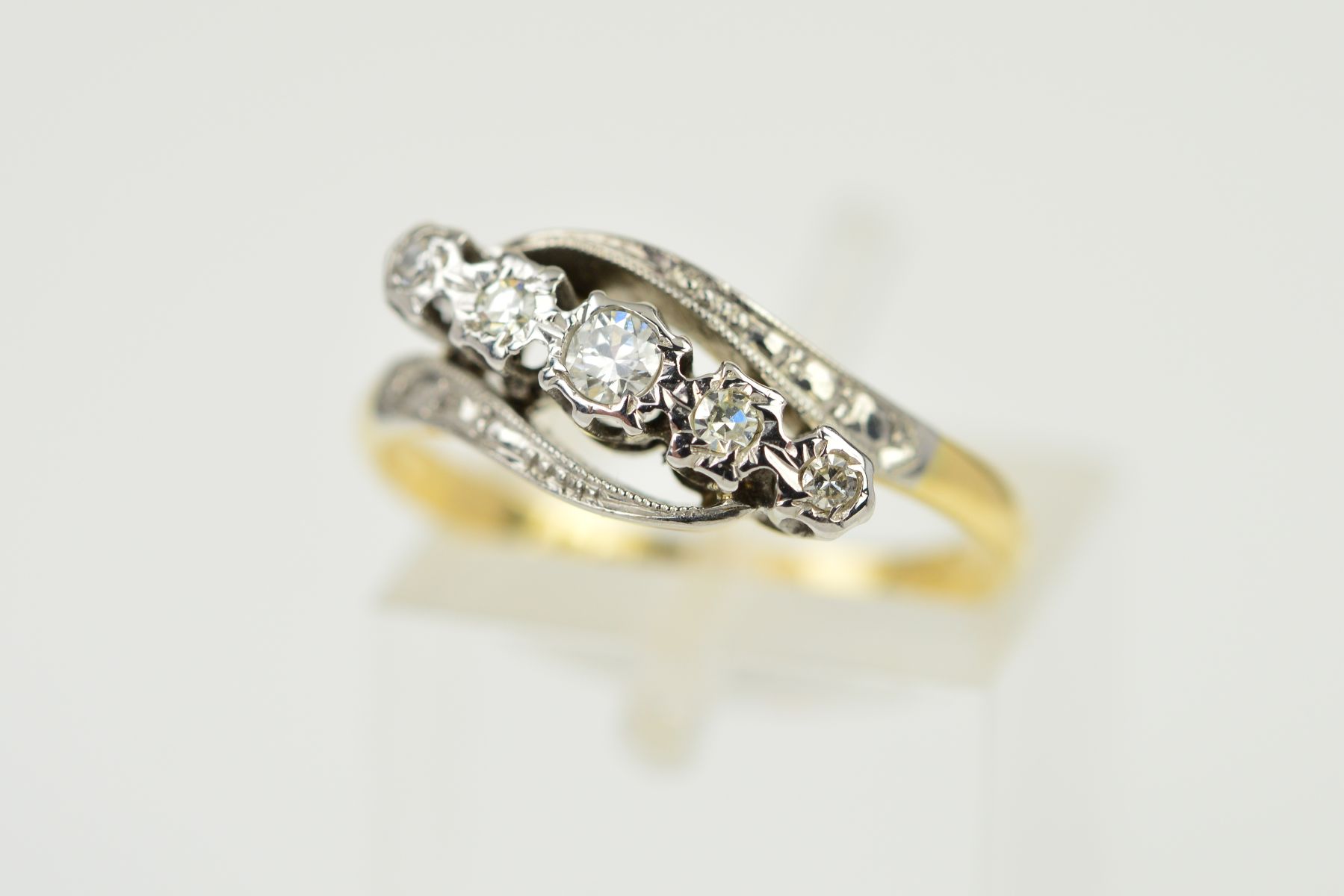 A FIVE STONE DIAMOND CROSSOVER RING, the graduated diamonds within illusion settings, the centre a