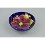 A SMALL MOORCROFT FOOTED BOWL, 'Clematis' pattern on blue ground, impressed marks to base,