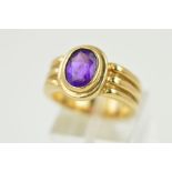 AN AMETHYST RING, the oval amethyst within a collet setting to the triple banded shank, stamped 9ct,