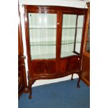 AN EDWARDIAN MAHOGANY SERPENTINE TWO DOOR DISPLAY CABINET, the double doors revealing two glass