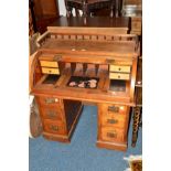 AN EDWARDIAN WALNUT ROLL TOP DESK, with a spindled gallery top, fitted interior with pull out