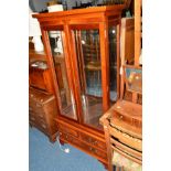 A REPRODUCTION CHERRYWOOD TWO DOOR DISPLAY CABINET above two short and a single long drawer, width