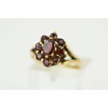 A 9CT GOLD GARNET CLUSTER RING, the central oval garnet within a circular garnet surround to the