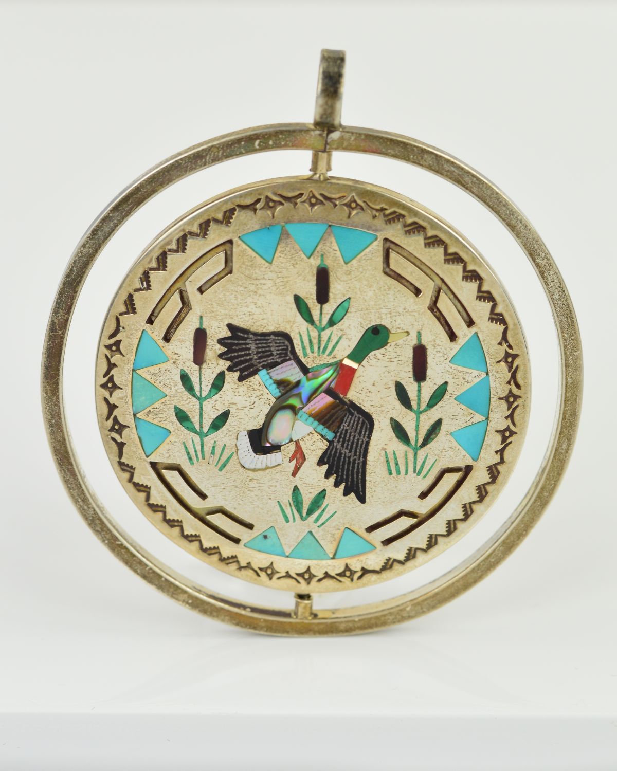 A PENDANT of circular outline, the central rotating disc within a circular surround, the central
