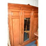 AN EDWARDIAN WALNUT THREE DOOR COMPACTUM WARDROBE, central bevelled edge mirror door, revealing