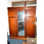 AN EDWARDIAN MAHOGANY THREE DOOR COMPACTUM WARDROBE, the central bevelled edge mirror door revealing