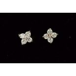 A PAIR OF 9CT GOLD DIAMOND EAR STUDS, each designed as four brilliant cut diamonds in a floral