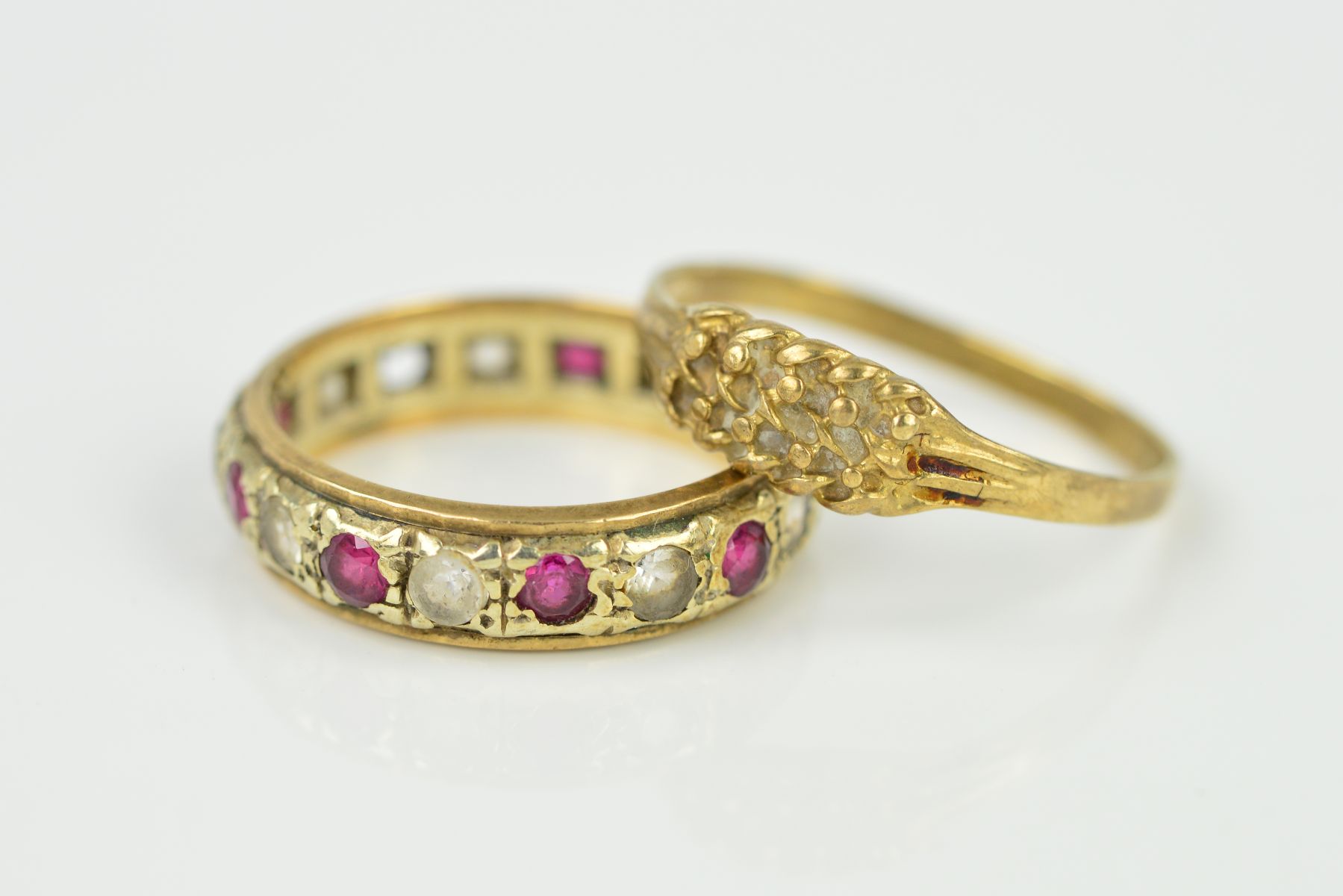 TWO 9CT GOLD RINGS, the first with a textured front panel and tapered shoulders to the plain band,