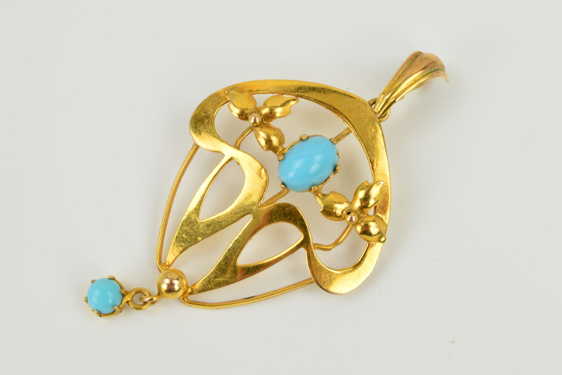 AN OPENWORK PENDANT of scrolling openwork design with foliate detail, set with an oval blue paste
