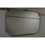A BRASSED FRAMED BEVELLED EDGE WALL MIRROR with canted corners and ribbon top, 95.5cm x 57cm