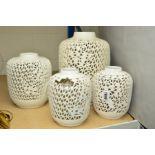 A SET OF FOUR WHITE GLAZED LAMP BASES, pierced with prunus blossom and bamboo designs, holes in