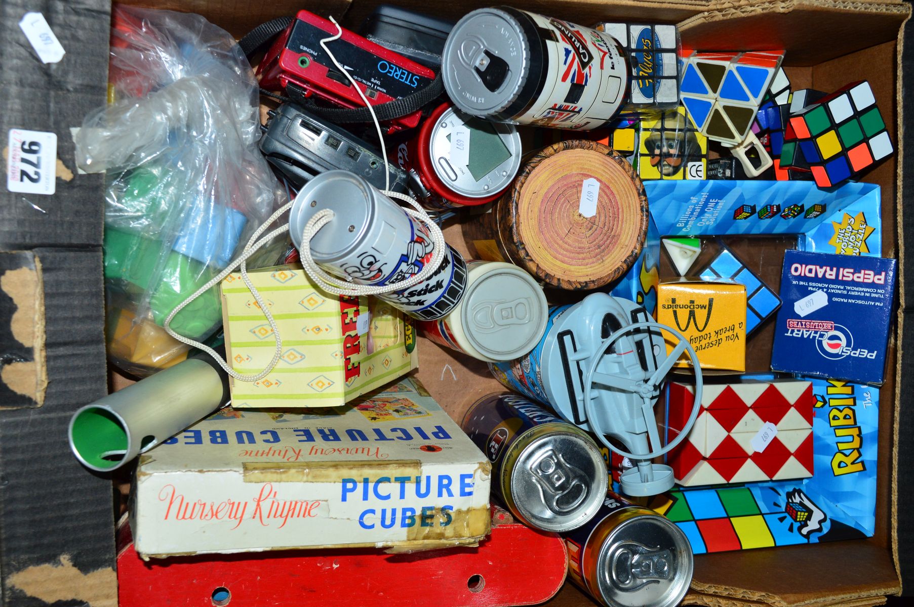 A BOX OF MISCELLANEOUS ITEMS, to include Rubik cubes, novelty cans (Coca-Cola radio alarm, camera