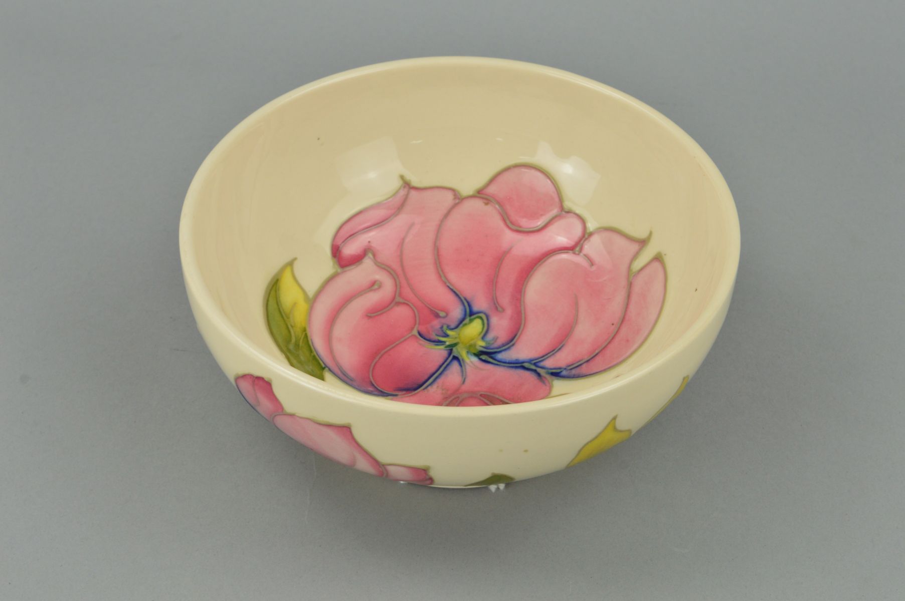 A MOORCROFT POTTERY FOOTED BOWL, 'Magnolia' pattern both inside and outside on a cream ground,