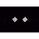 A PAIR OF DIAMOND EAR STUDS each designed as a princess cut diamond within a four claw setting,