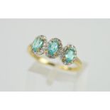 A 9CT GOLD APATITE AND DIAMOND RING, designed as three oval Apatites each within single cut