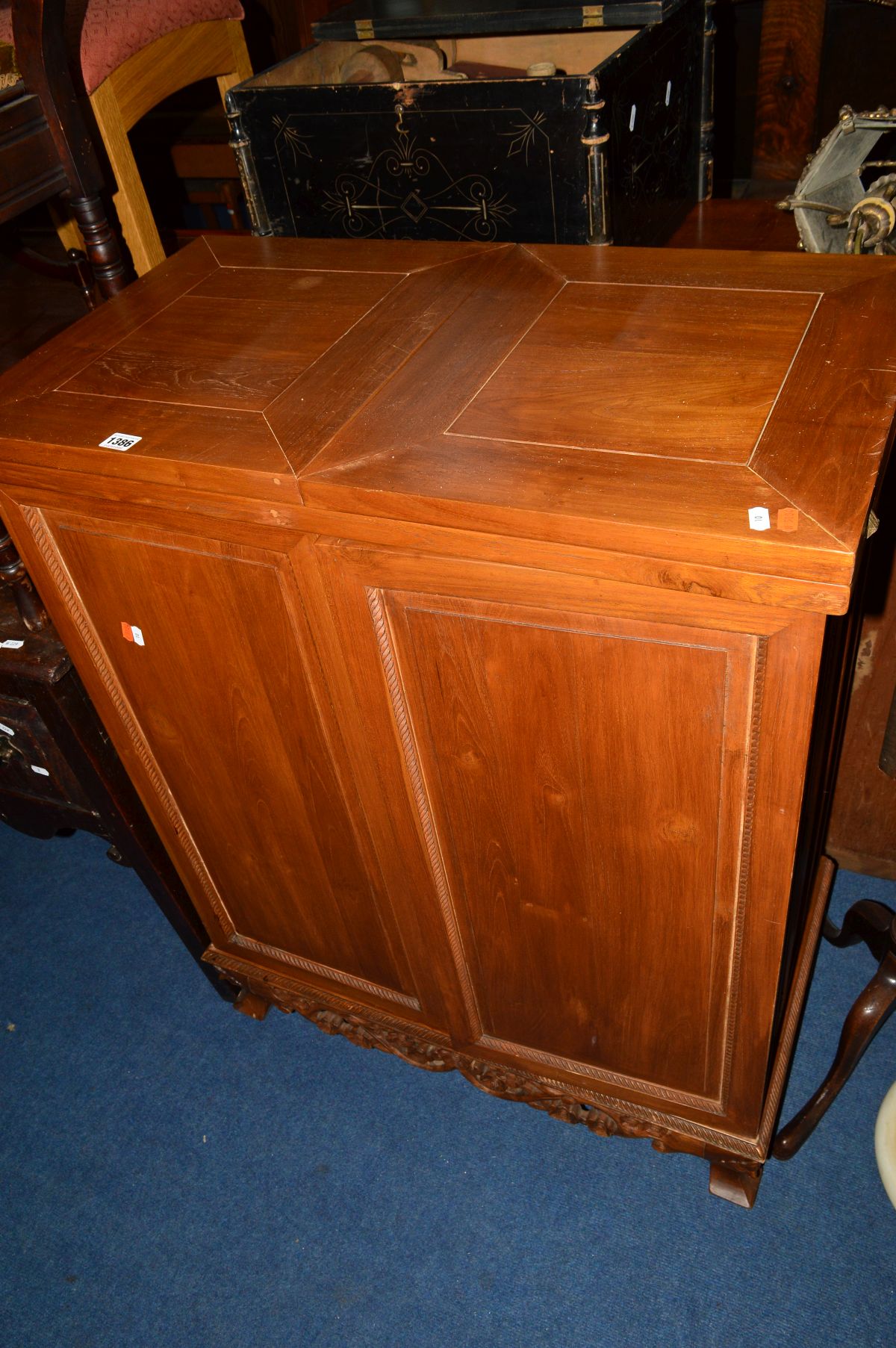 A HARDWOOD DRINKS BAR, the double fold over top supported on doors revealing a fitted interior,