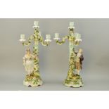 A PAIR OF CONTINENTAL PORCELAIN FIGURAL CANDELABRAS, encrusted with roses and foliage, height