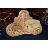 AN EDWARDIAN OAK AND FLORALLY UPHOLSTERED THREE SEATER CONVERSATION SETTEE, on brass caps and