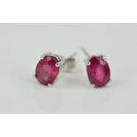 A PAIR OF 9CT WHITE GOLD RUBY EAR STUDS, each designed as an oval ruby within a four claw setting,