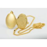 A 9CT GOLD LOCKET AND CHAIN, the locket of oval outline with engraved scrolling and floral