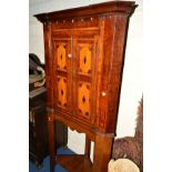 A GEORGIAN OAK AND ROSEWOOD BANDED PANELLLED TWO DOOR CORNER CUPBOARD, on a later stand with an