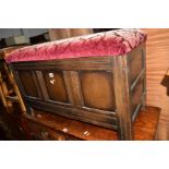 AN OAK PANELLED BLANKET CHEST, with an upholstered top