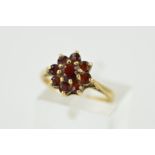 A 9CT GOLD GARNET CLUSTER RING, designed as a tiered circular garnet cluster to the tapered