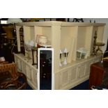 TWO MATCHING LARGE CREAM PAINTED OPEN BOOKCASES, with adjustable shelving above six lattice cupboard