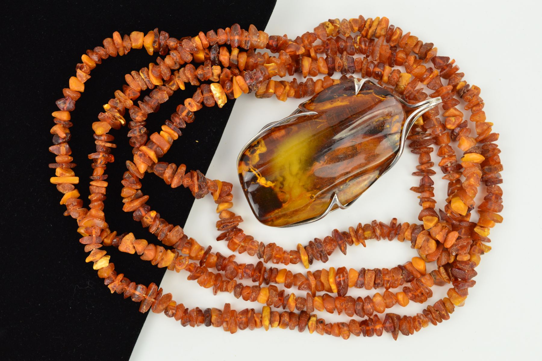 AN AMBER NECKLACE AND PENDANT, the pendant designed as a large polished piece of amber within an