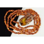 AN AMBER NECKLACE AND PENDANT, the pendant designed as a large polished piece of amber within an