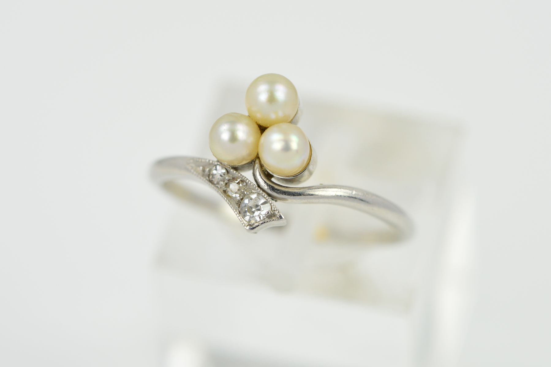 AN EARLY 20TH CENTURY PEARL AND DIAMOND TREFOIL CROSSOVER RING, ring size L, personal inscription on