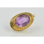 A 9CT GOLD AMETHYST BROOCH/PENDANT, designed as a central oval amethyst within a collet setting to