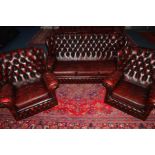 A RED LEATHER CHESTERFIELD THREE PIECE LOUNGE SUITE, comprising of a three seater settee and a