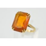A 9CT GOLD ORANGE PASTE RING, designed as a rectangular orange paste within a double four claw