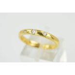 AN 18CT GOLD DIAMOND BAND RING, the plain band flush set with three graduated brilliant cut