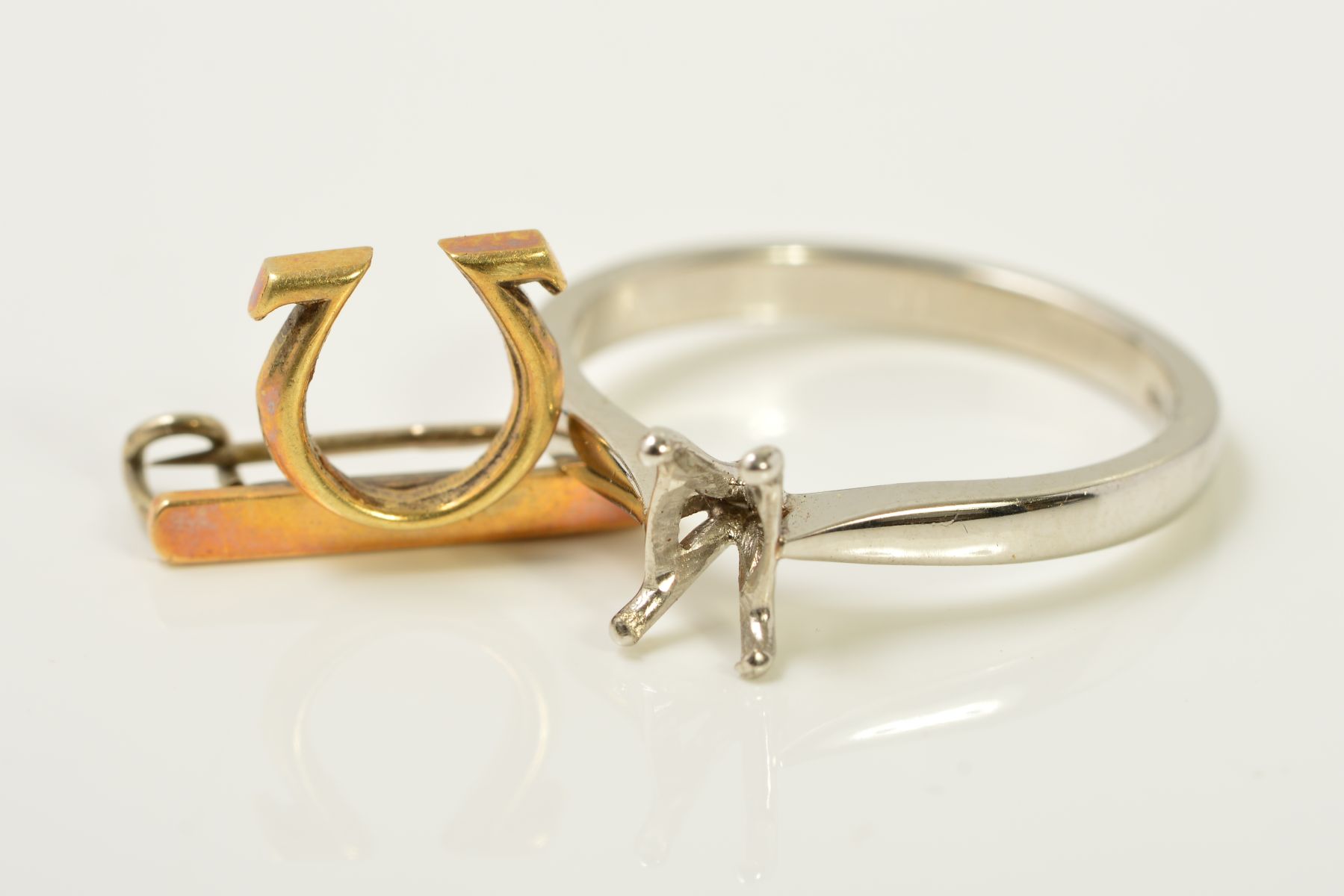 A PLATINUM RING MOUNT AND AN OMEGA PIN BROOCH, the platinum ring mount with four claws, with