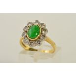 AN 18CT GOLD JADE AND DIAMOND CLUSTER RING, designed as a central oval jade cabochon within a collet