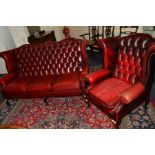 A BUTTONED OXBLOOD LEATHER TWO PIECE LOUNGE SUITE, comprising a winged three seater settee and a