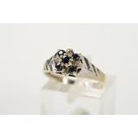 A 9CT WHITE GOLD SAPPHIRE AND DIAMOND CLUSTER RING, designed as a central, raised circular sapphire,