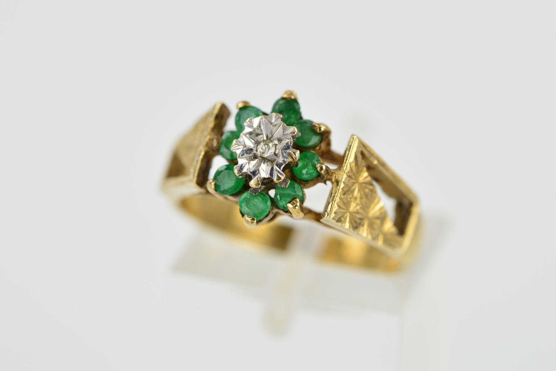 A 9CT GOLD EMERALD AND DIAMOND CLUSTER RING, designed as a central single cut diamond within an